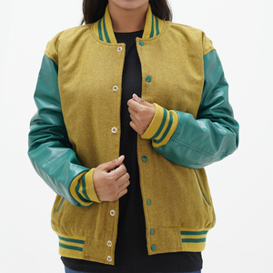 A woman wearing a camel body and green leather sleeves varsity jacket with a standing collar, ribbed cuffs, and green stripes on the sleeves.