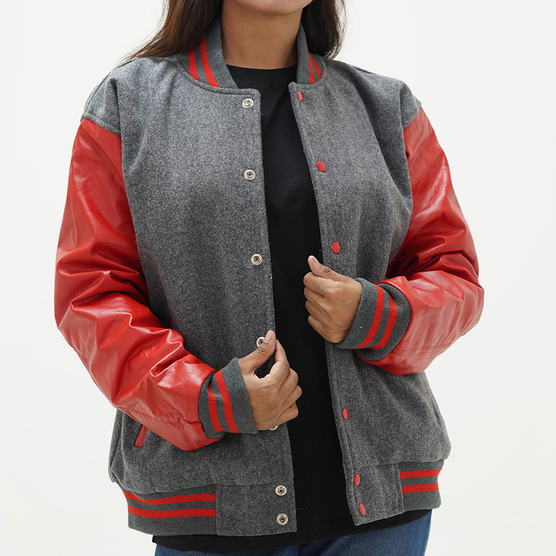A woman wearing a grey and red leather sleeves wool body varsity jacket with a standing collar, ribbed cuffs, and side pockets.