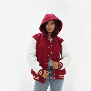 Three-quarter view of women's magenta hooded varsity jacket highlighting snap buttons, hood detail, side pockets, and magenta-white color scheme