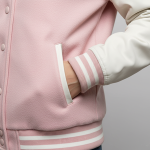 Close-up of a pink varsity jacket with white stripes on a neutral background