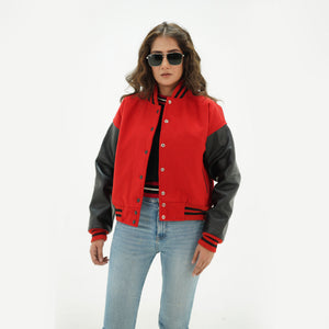 Three-quarter view of women's red and black varsity jacket highlighting snap buttons, side pockets, and bold red-black color contrast