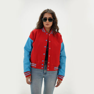 Three-quarter view of women's red and sky blue varsity jacket highlighting snap buttons, side pockets, and vibrant red-sky blue color combination