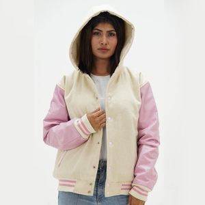 A woman wearing a hooded jacket with off white wool body and pink leather sleeves, featuring a front hood, ribbed cuffs, and a standing collar.