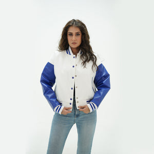 Three-quarter view of women's white and blue crop varsity jacket highlighting snap buttons, cropped waist, and fresh white-blue color scheme