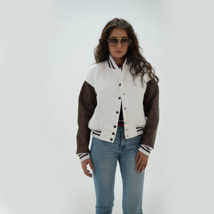 Three-quarter angle of women's white and chocolate brown varsity jacket highlighting snap buttons, side pockets, and elegant white-chocolate brown color pairing