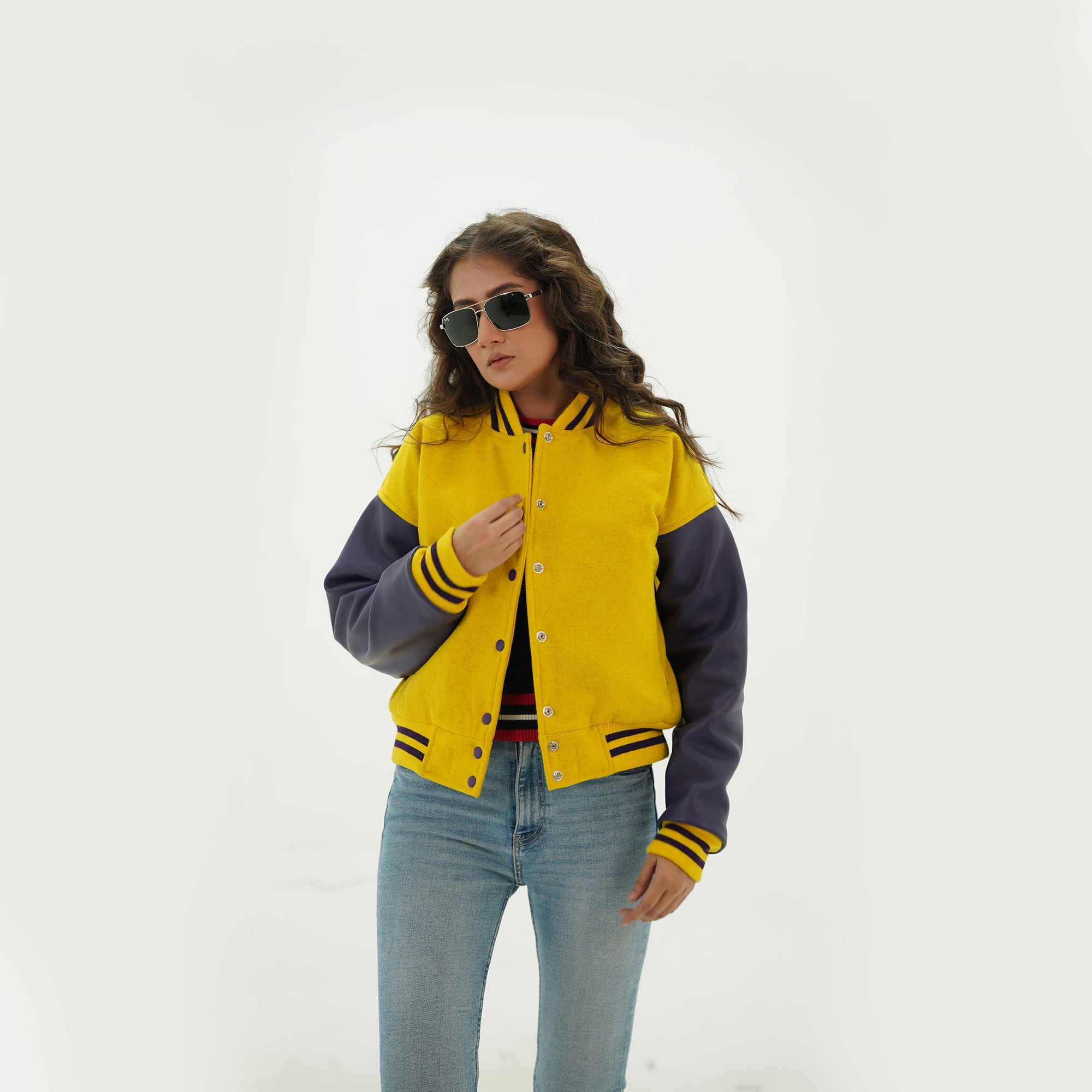 Three-quarter angle of women's yellow and blue varsity jacket highlighting snap buttons, side pockets, and vibrant yellow-blue color scheme