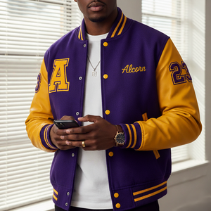 Person wearing a purple and yellow 'Alcorn' letterman jacket holding a phone.