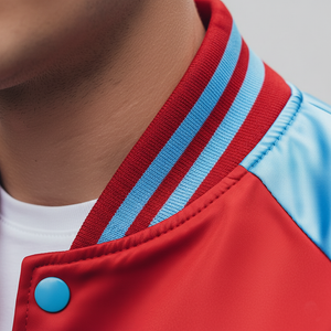 Close-up of a red jacket with blue stripes and button, worn by a person. 