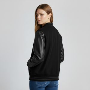 Woman wearing a black bomber jacket with leather sleeves on a light gray background
