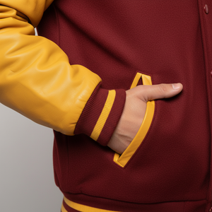 Maroon and yellow varsity jacket with a hand in the pocket against a neutral background