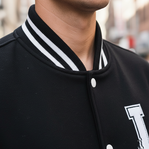 Black varsity jacket with white stripes and lettering on a blurred background