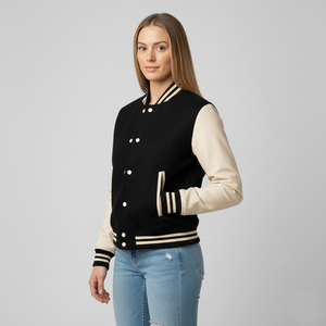 Woman wearing a black and cream varsity jacket side angle on a gray background