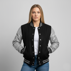 Woman wearing a black and gray varsity jacket on a gray background