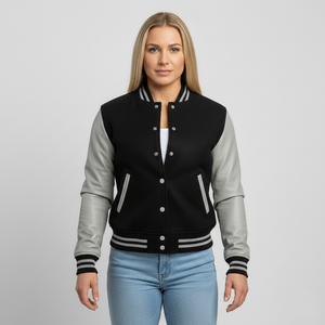 Woman wearing a black and gray varsity jacket on a plain background