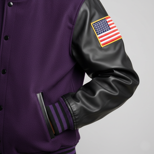 Purple varsity jacket with black leather sleeves and American flag patch on a gray background