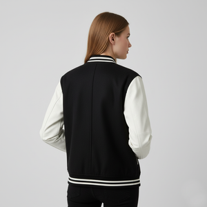 Person wearing a black and white varsity jacket on a gray background