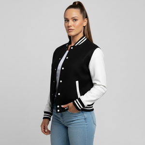 Woman wearing a black and white varsity jacket on a gray background