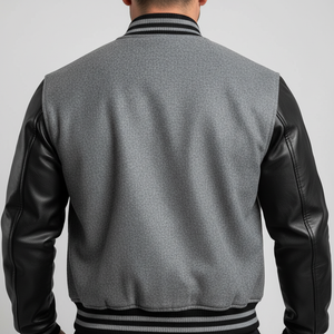 Gray varsity jacket with black leather sleeves on a gray background
