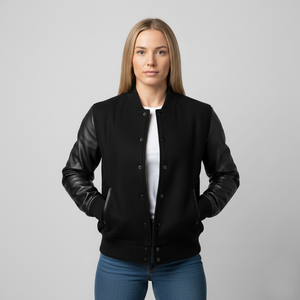 Woman wearing a black bomber jacket with leather sleeves on a gray background