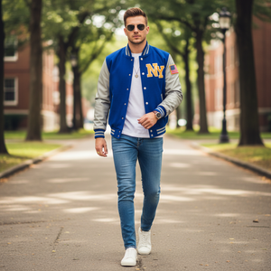 Man wearing a blue and gray varsity jacket with 'NY' on it, walking on a tree-lined street.