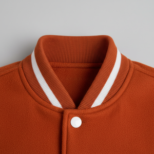Close-up of an orange jacket with a white collar and button on a gray background 
