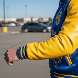 Person wearing a blue and yellow letterman jacket with a blurred parking lot background