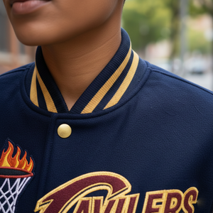 Navy blue varsity jacket with gold accents and a logo on a blurred street background