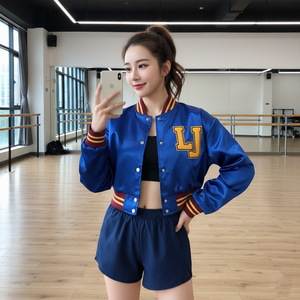 Woman taking a selfie in a dance studio wearing a blue jacket with 'LJ' and navy shorts.