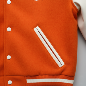 Close-up of an orange varsity jacket with white stripes and buttons.