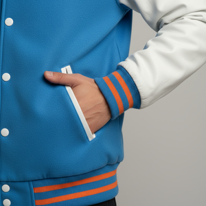 Person wearing a blue varsity jacket with orange stripes on a gray background