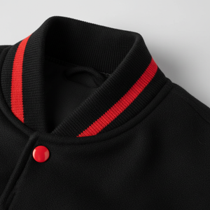 Close-up of a black cardigan with red stripes on the collar against a gray background