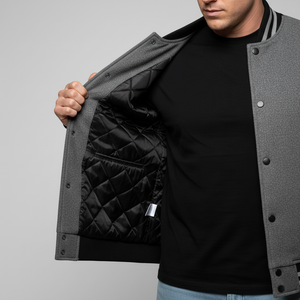Person wearing a gray jacket with quilted black lining, standing against a plain background