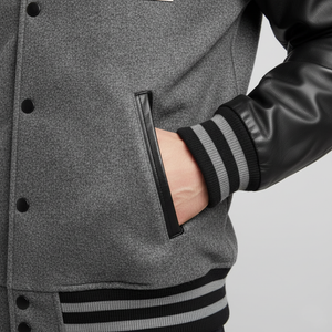 Gray varsity jacket with black and gray striped sleeves on a neutral background