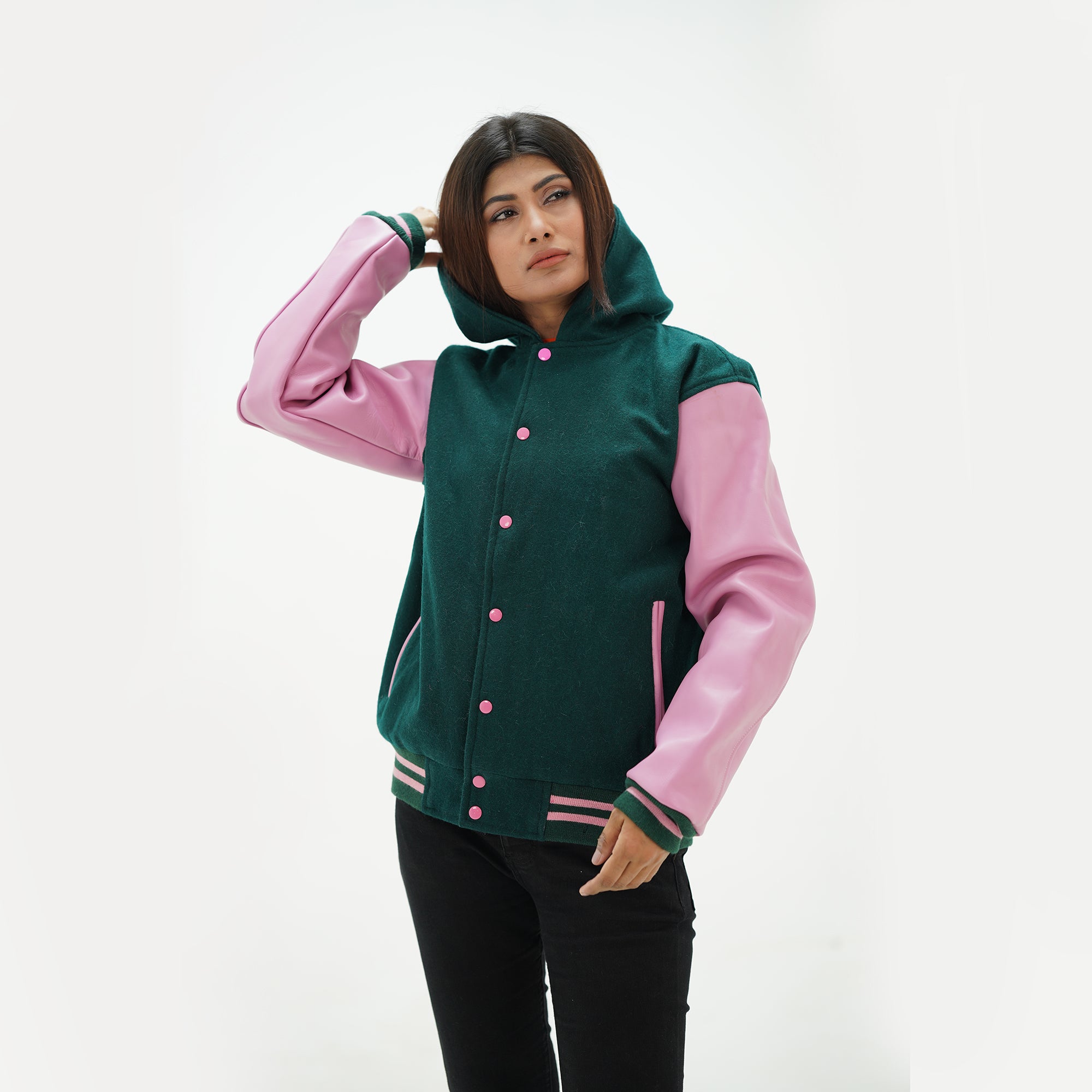 Three-quarter angle of green baseball jacket with adjustable hood and pink leather sleeves showing wool construction