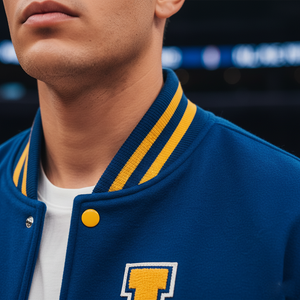 Close-up of a person wearing a blue varsity jacket with yellow accents and a large 'I' emblem.