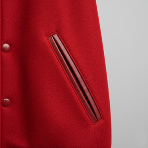 Close-up of a red coat with a button and pocket on a gray background