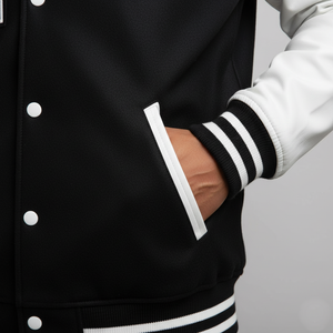 Black varsity jacket with white and black striped sleeves on a gray background