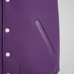 Close-up of a purple garment with a pocket and buttons on a gray background