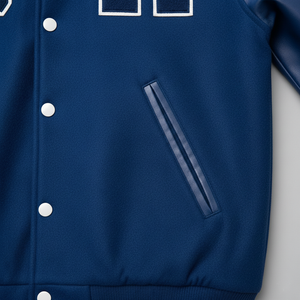 Close-up of a blue varsity jacket with white buttons and a pocket on a light gray background