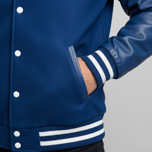 Close-up of a blue varsity jacket with white buttons and stripes on a gray background