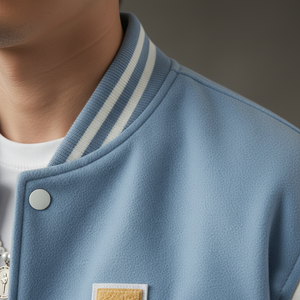 Close-up of a person wearing a light blue varsity jacket with white stripes on the collar.