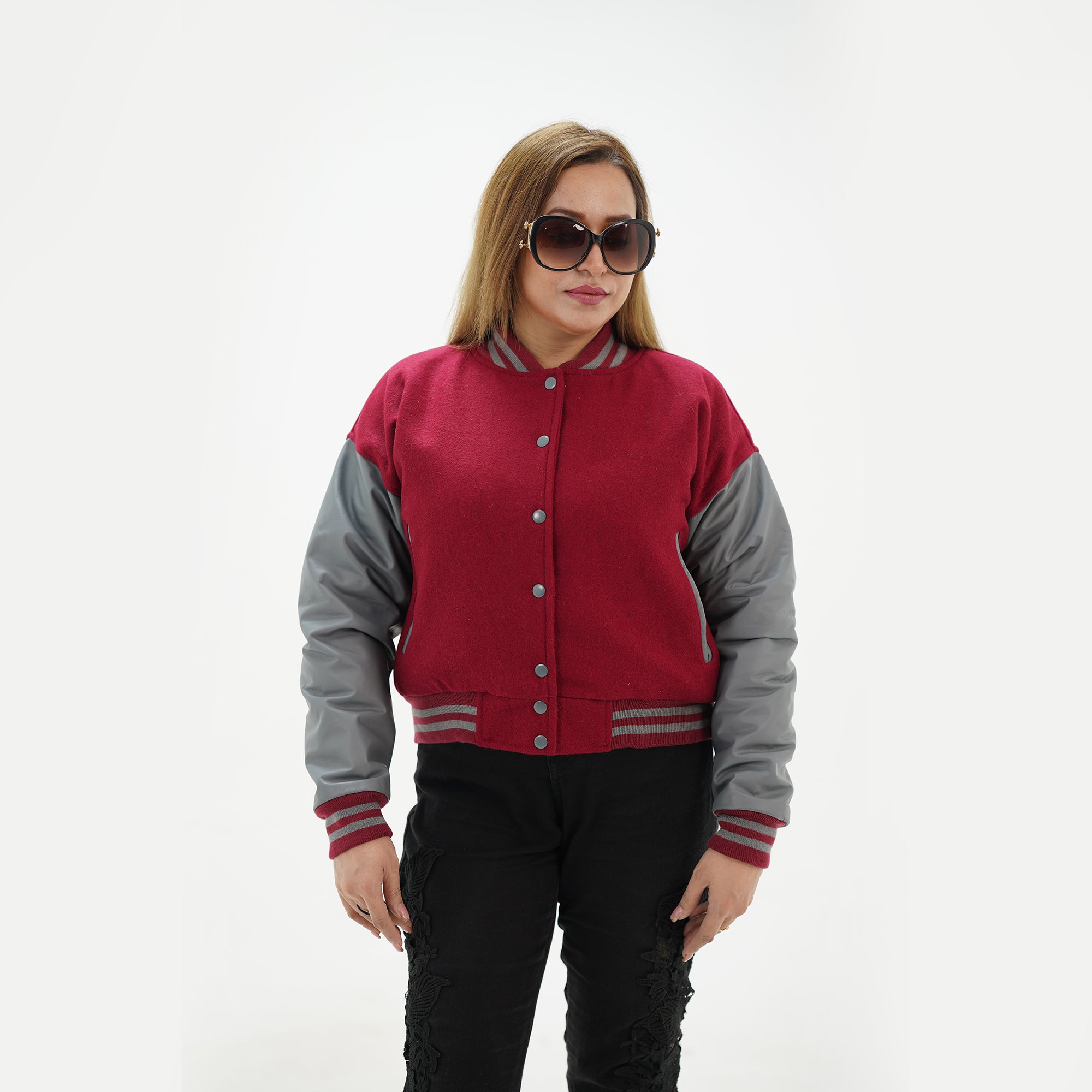 Close-up detail of magenta and gray varsity jacket featuring magenta wool and gray leather sleeve junction with ribbed collar trim accents