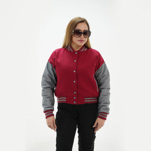 Close-up detail of magenta and gray varsity jacket featuring magenta wool and gray leather sleeve junction with ribbed collar trim accents