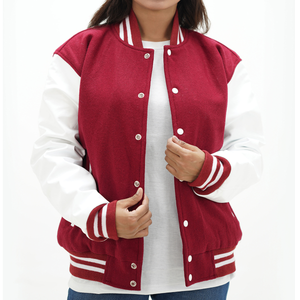 A woman wearing a magenta and white letterman jacket with leather arms and a wool body. It features a classic ribbed collar, white leather sleeves with red stripes, and two side pockets. 