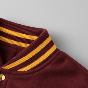 Close-up of a maroon jacket with yellow stripes on the collar against a gray background 