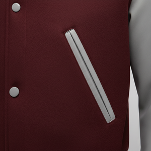 Close-up of a maroon jacket with a silver zipper and button on a gray background