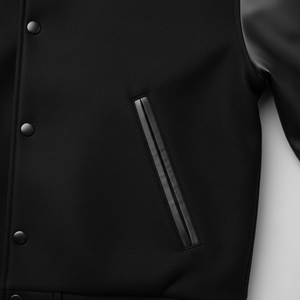 Close-up of a black varsity jacket with buttons and a pocket.