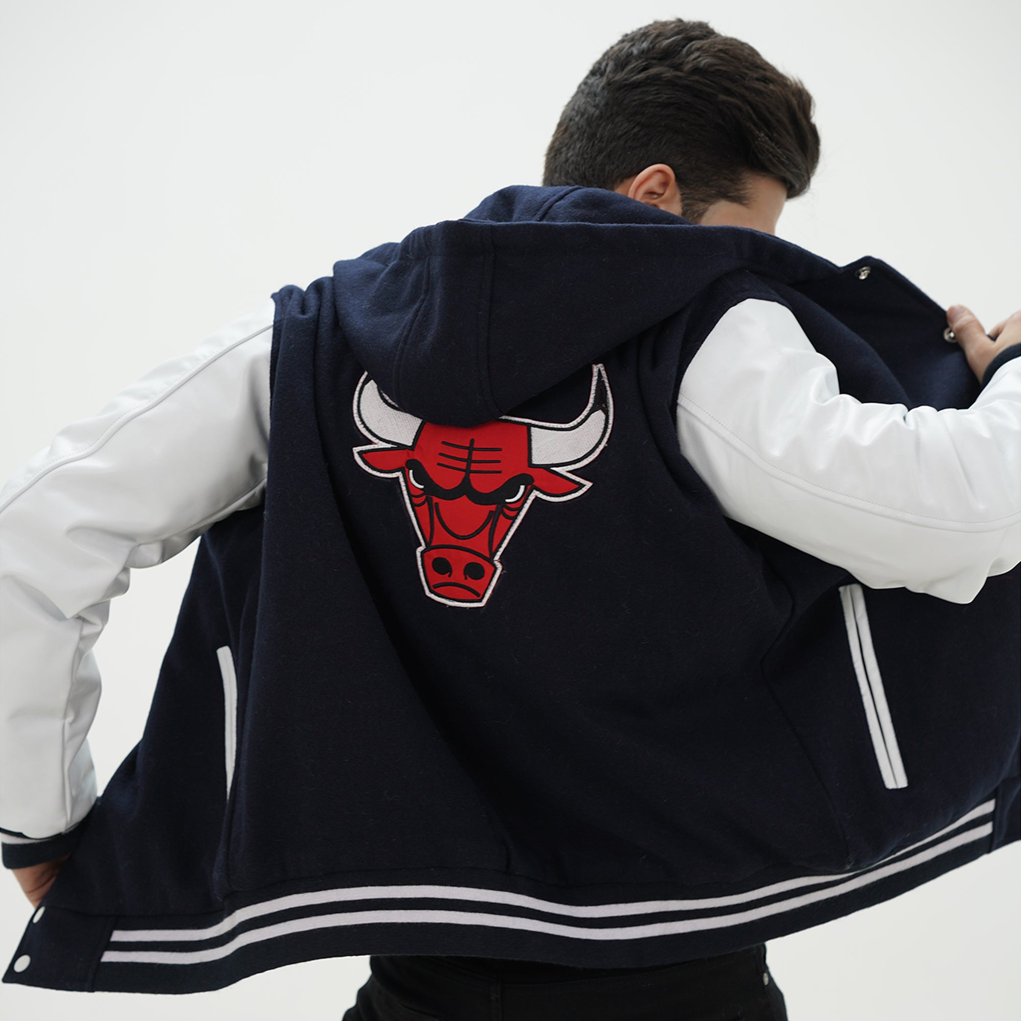 Three quarter view of men Chicago Bulls hooded jacket highlighting premium wool body and genuine leather sleeve materials for NBA fans