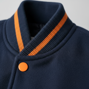 Navy blue jacket with orange trim and button on a light gray background
