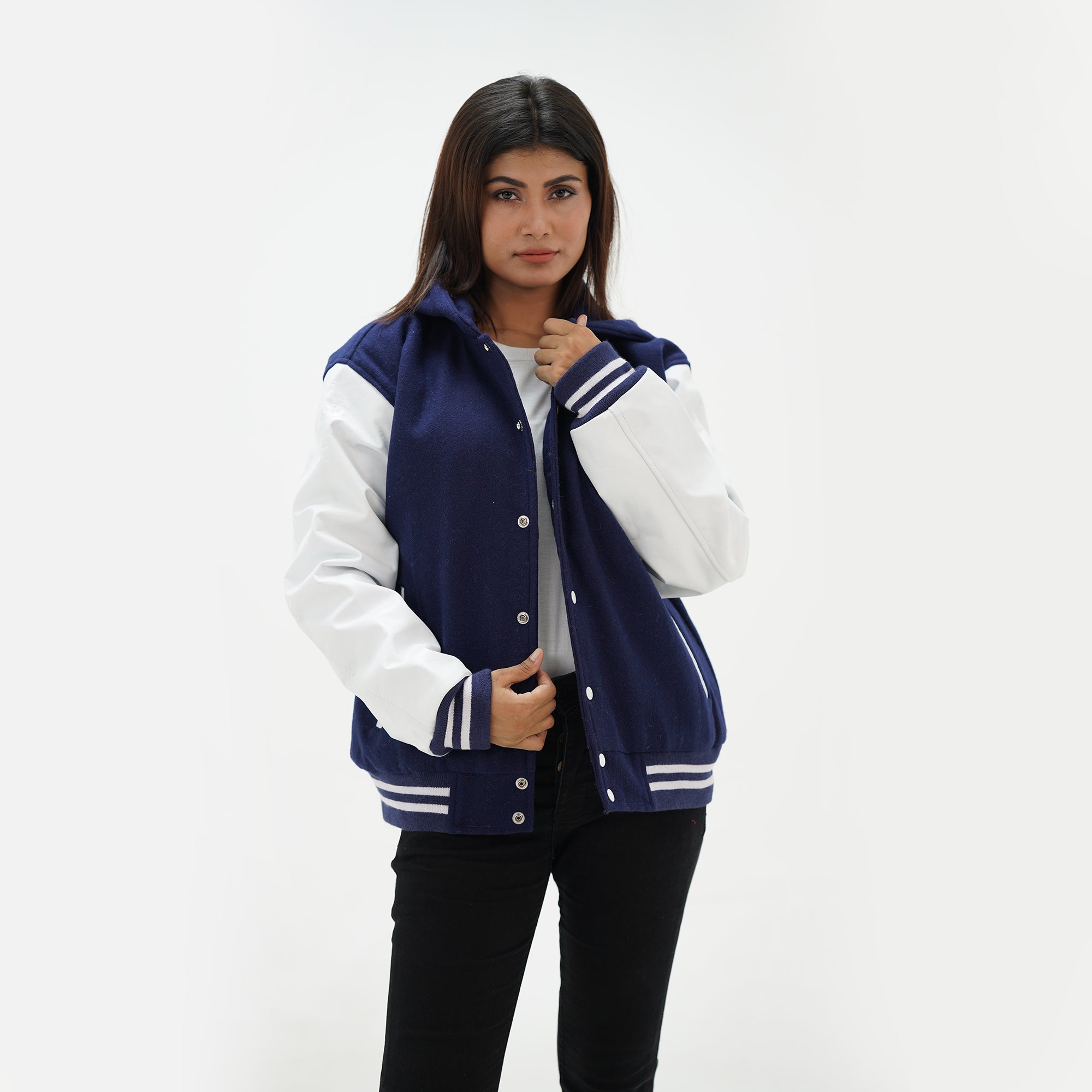 Detail shot of white leather sleeve and ribbed waistband with navy and white striped trim on women's hooded varsity jacket